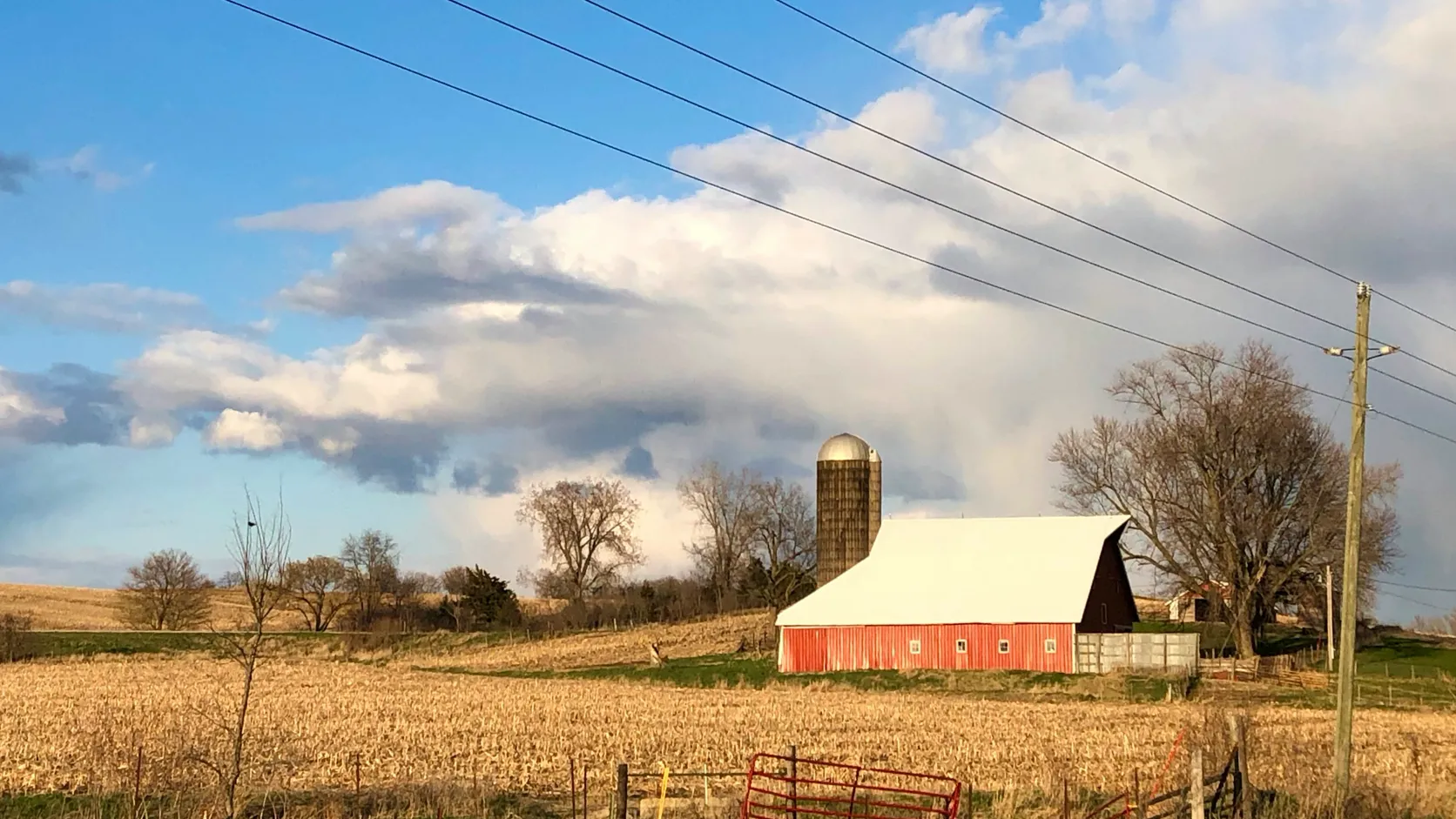 Small family feed mill with a red barn and grain silo in open farmland.